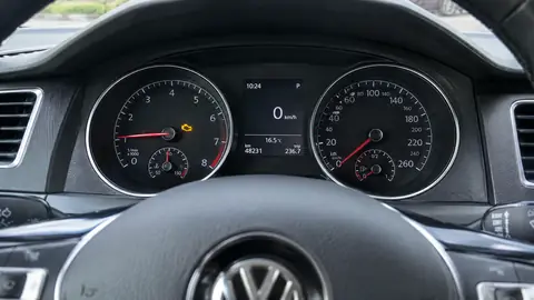 Gelbe Motorkontrollleuchte im Instrumentenbrett eines stehenden Volkswagen